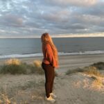 A girl standing in the sunset and gazing into the ocean