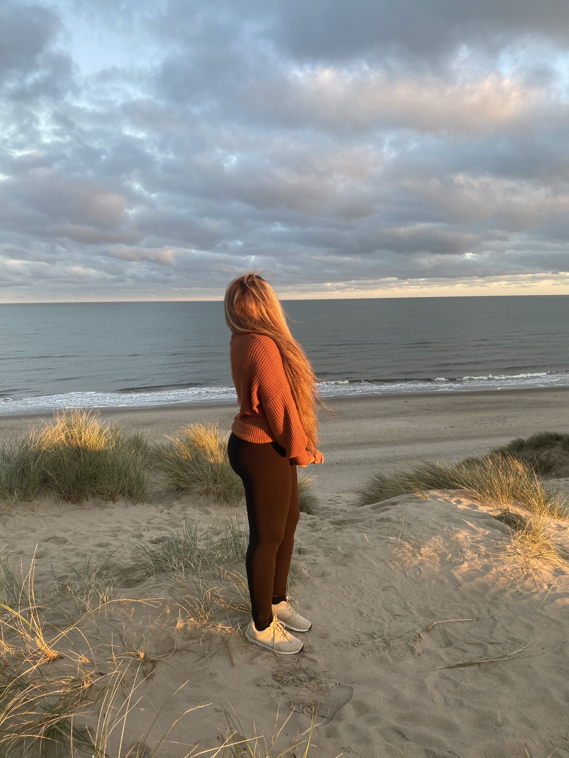 A girl standing in the sunset and gazing into the ocean