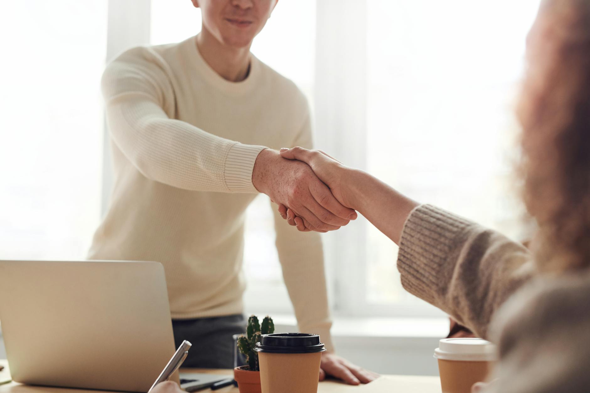 2 individuals shaking hands over a job offer.