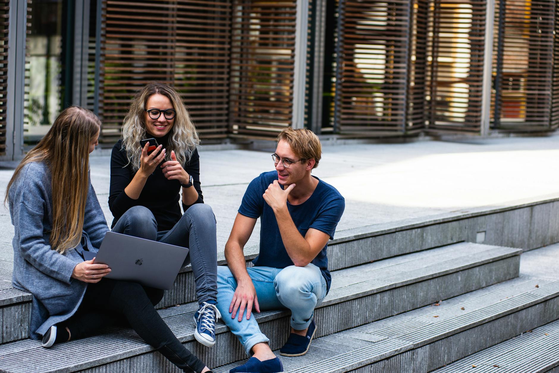 3 students sitting on the floor, discussing about their undergraduate courses in the UK.