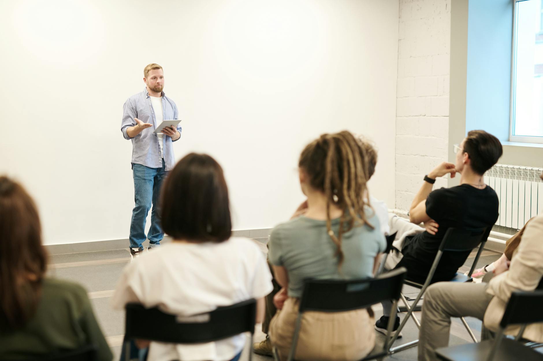 A male lecturer speaking to a class of university students