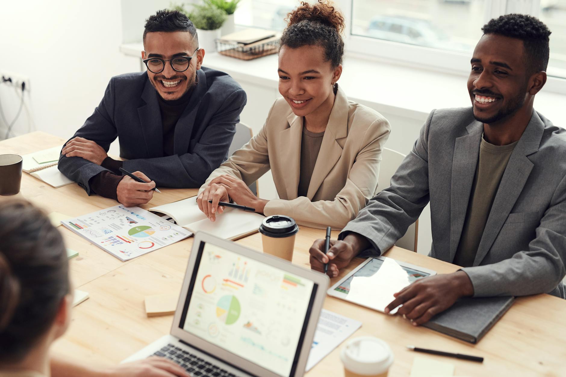 3 young professionals all smile in their meeting room.