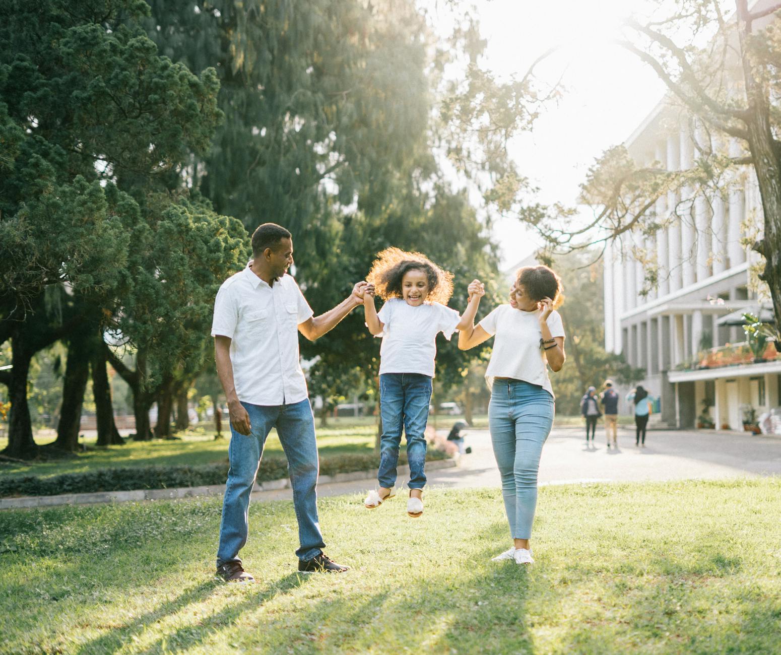 A young black family all joyful as the mum and dad lift a giggling baby in the air