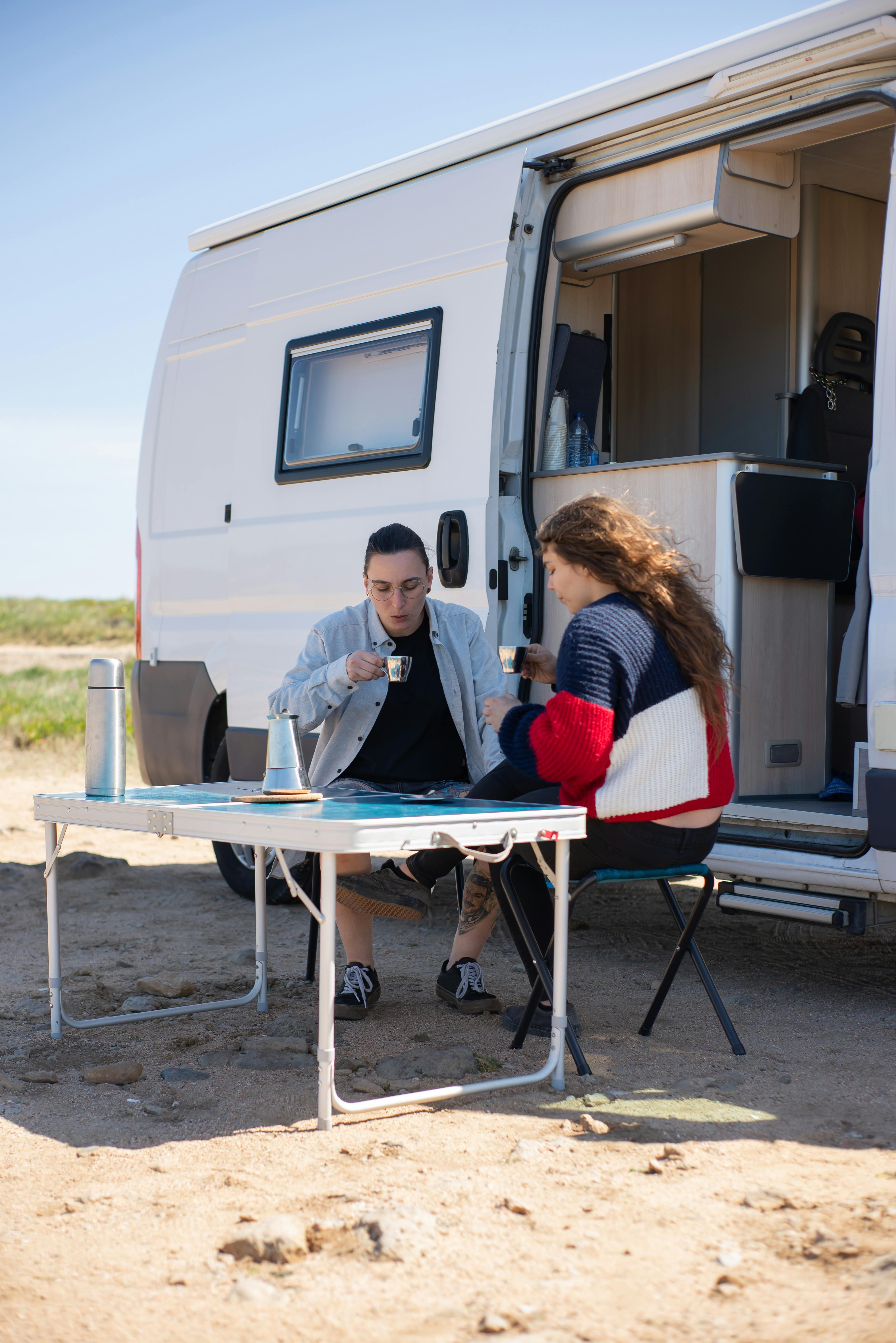 2 women sitting outside their van