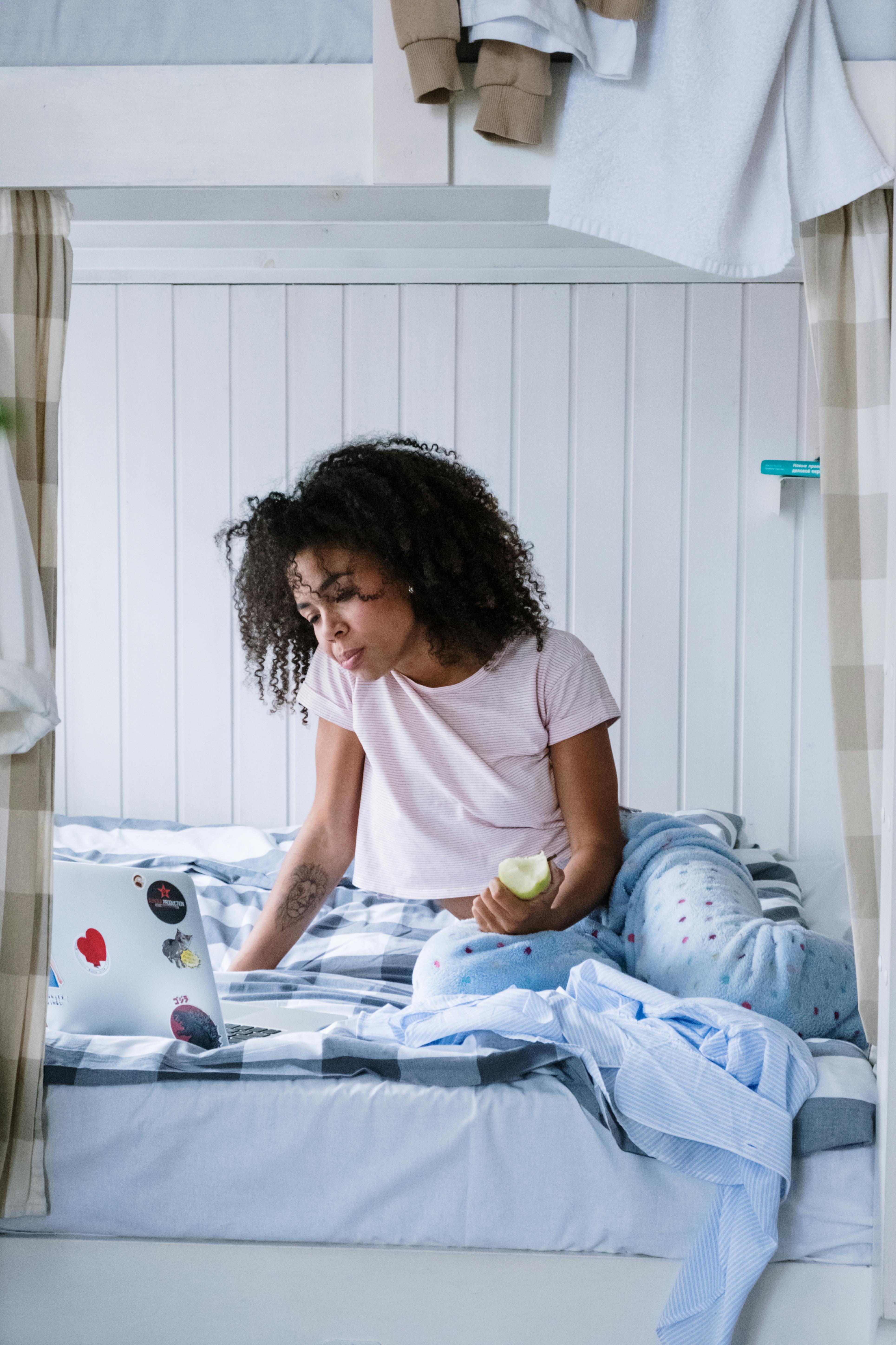 A FEMALE STUDENT READING ON HER BED