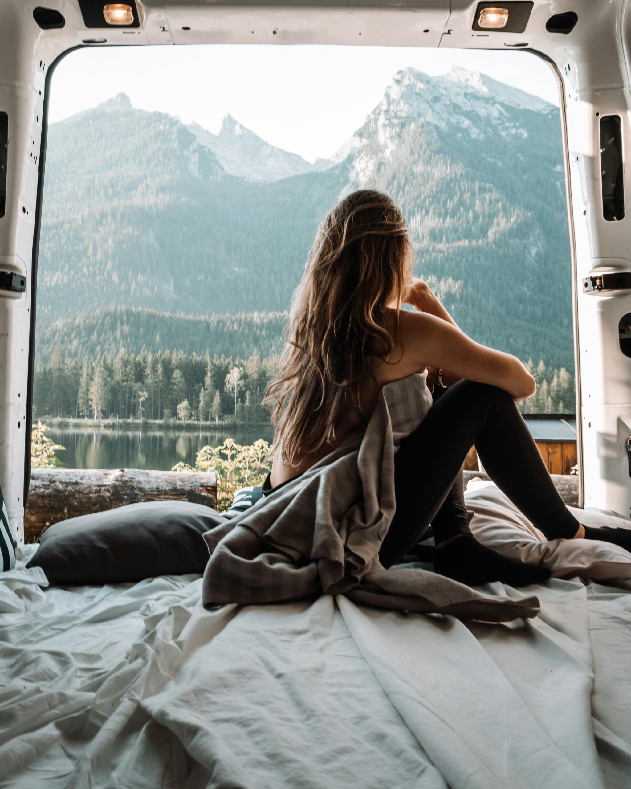 a girl sitting in her van and gazing at the sunset