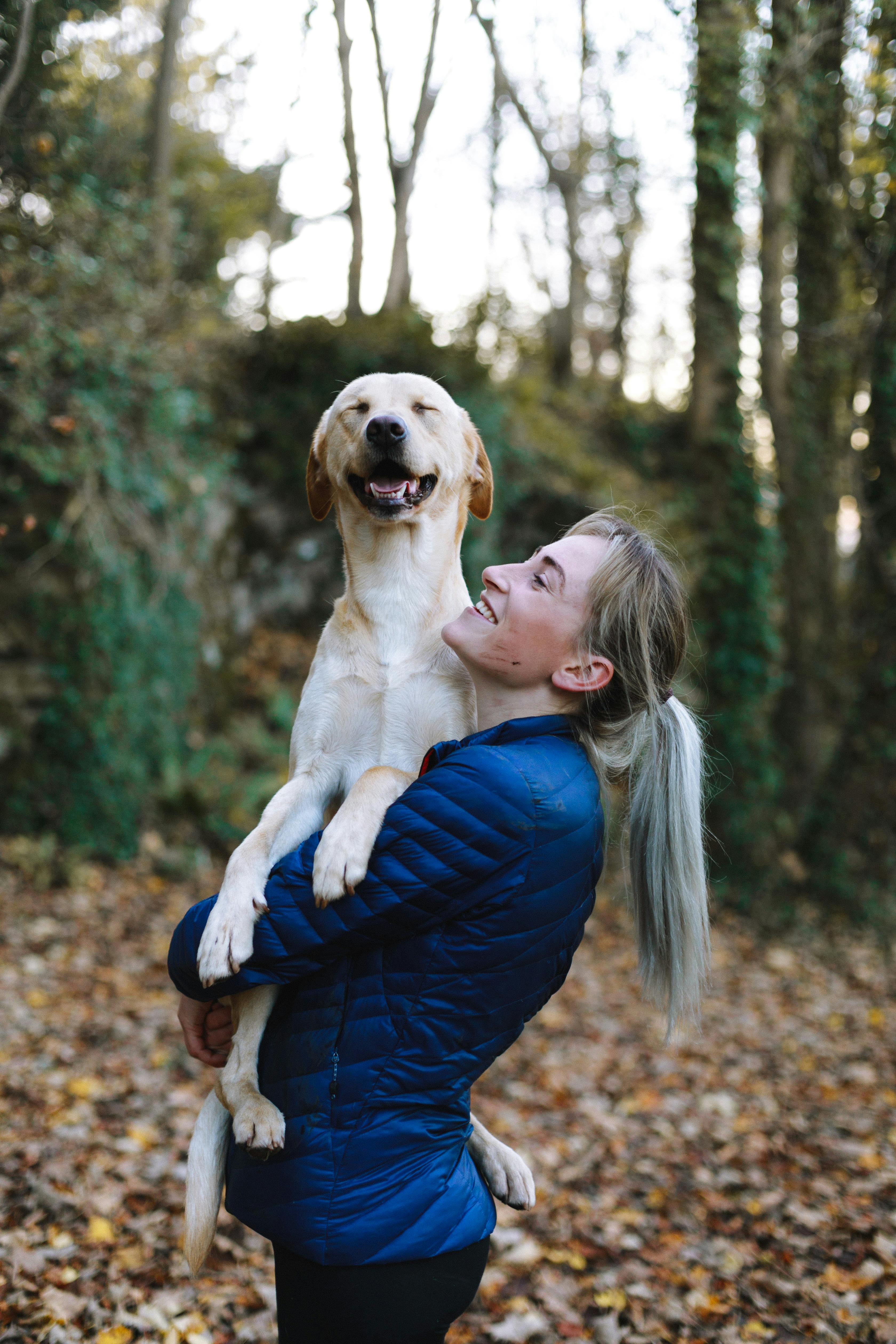 a woman carrying her dog from a van