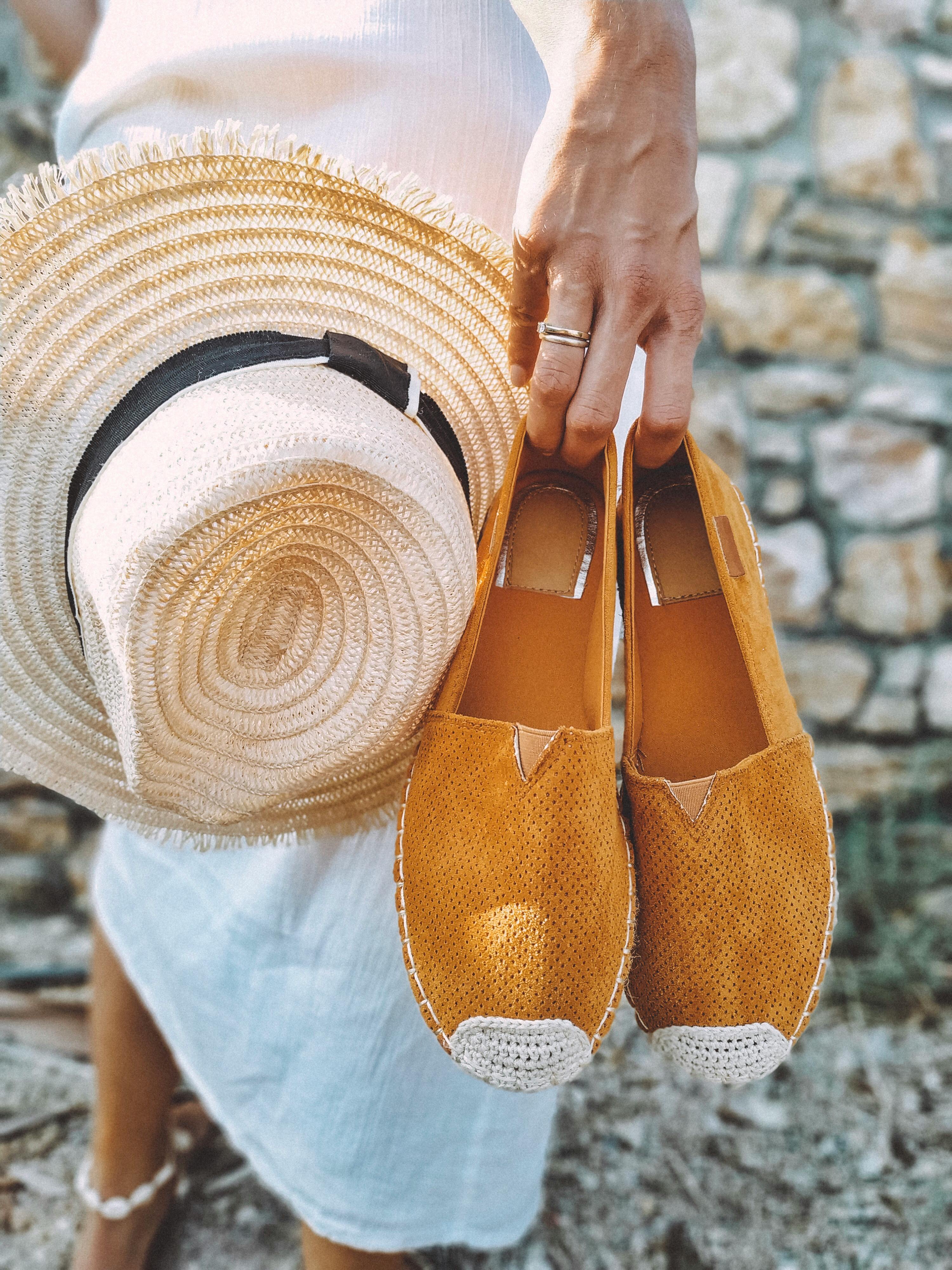 a woman holding beach hat and footwear