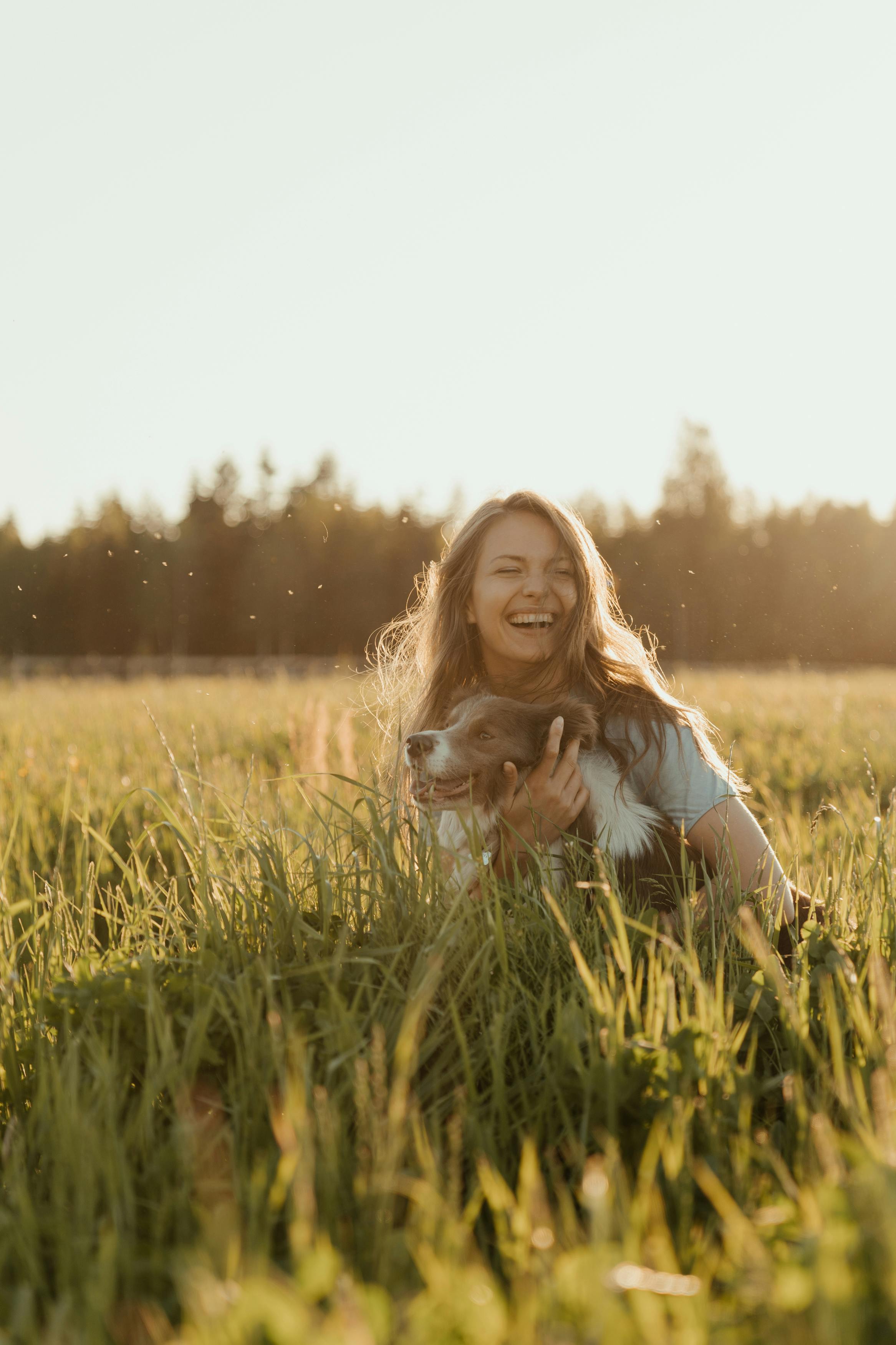 a woman and her dog sitting on grass