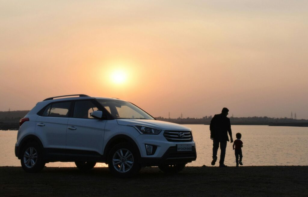 father and child viewing sunset outside their car