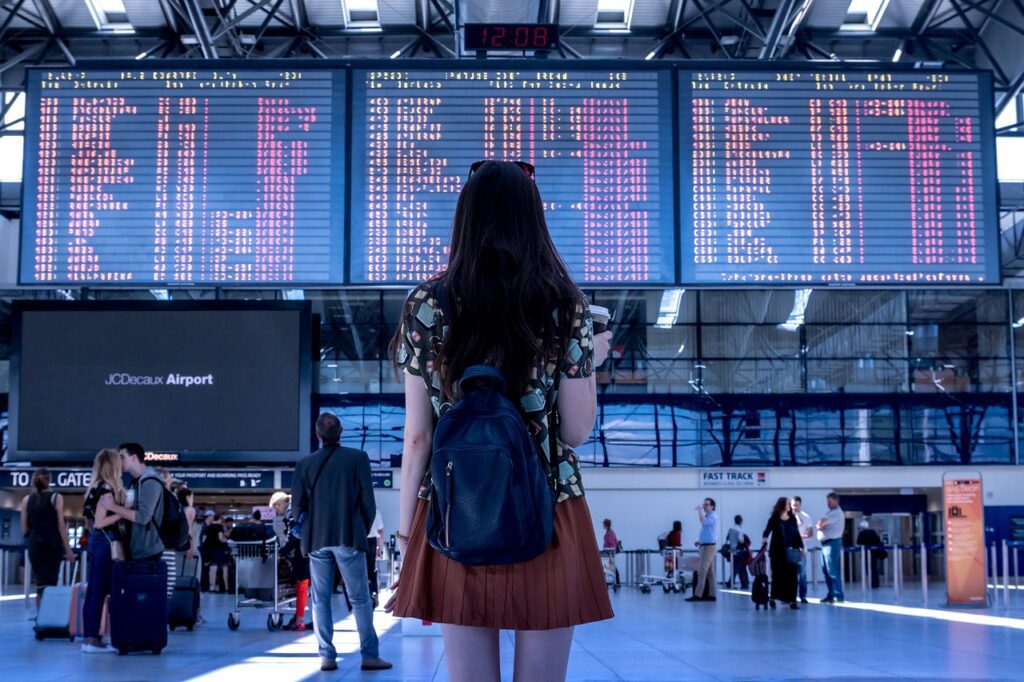 woman standing in front of delayed flight screen